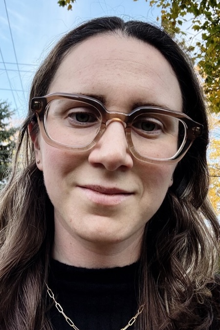 Headshot of Sarah Silverman: White woman with brown and blond hair, wearing a black shirt and brown glasses frames.