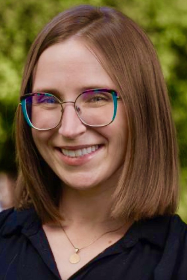 Headshot of Brie Tripp: White woman with brown hair, wearing a black shirt and glasses.